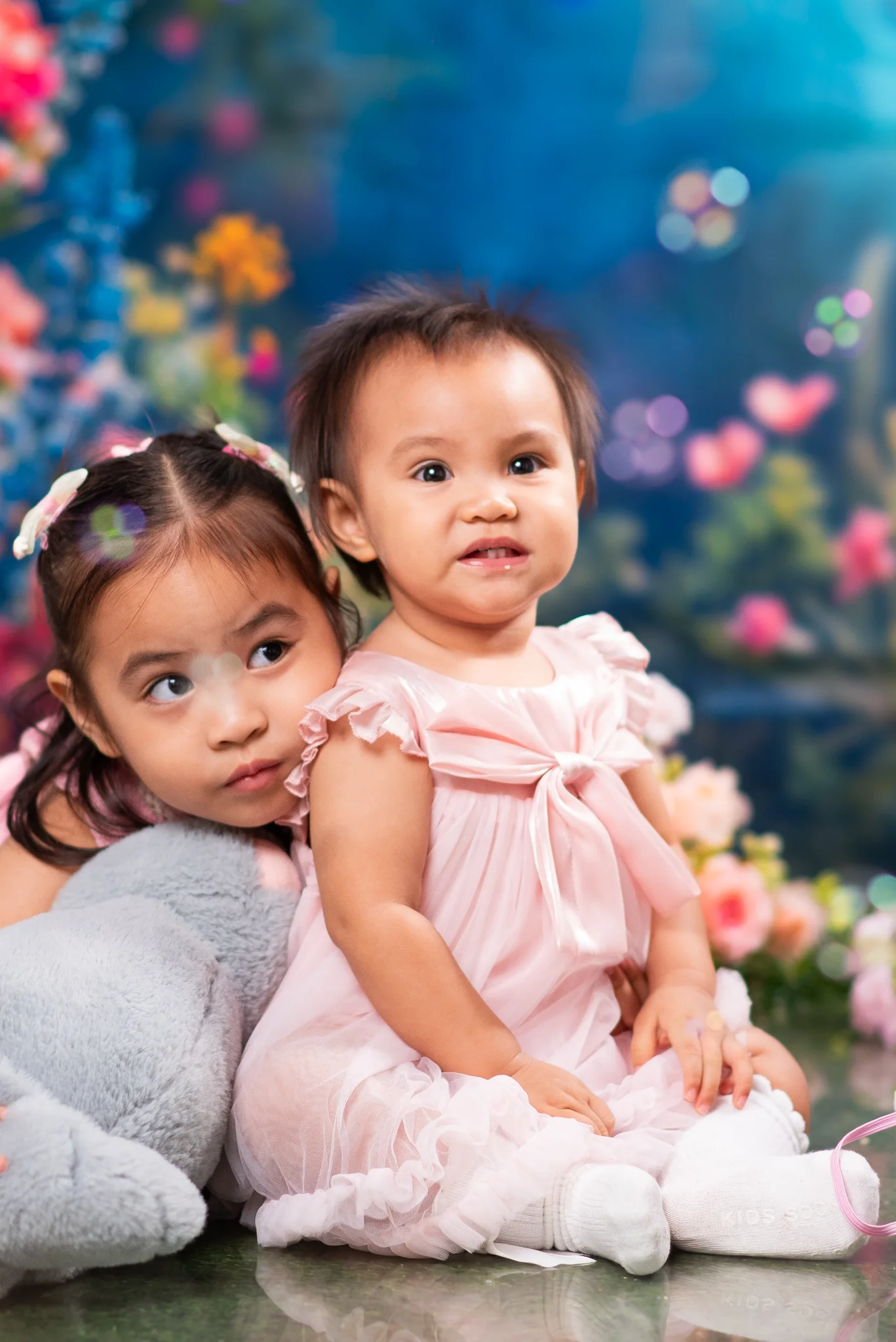 Julia in pink sitting beside her sister Jordy Olivia and a soft toy